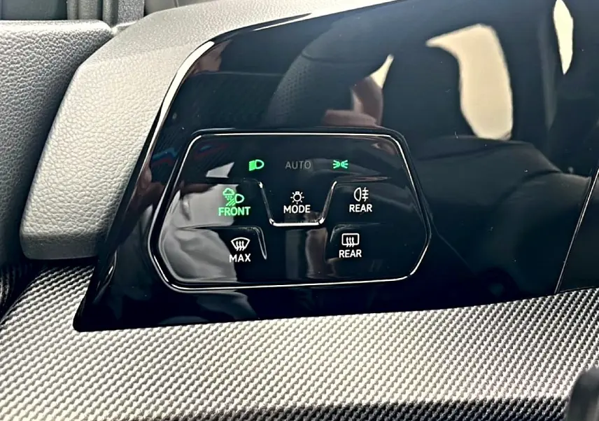 Gros plan sur les commandes d’éclairage et de dégivrage avec finition noire brillante et insert carbone dans une Volkswagen Golf noire 2026.