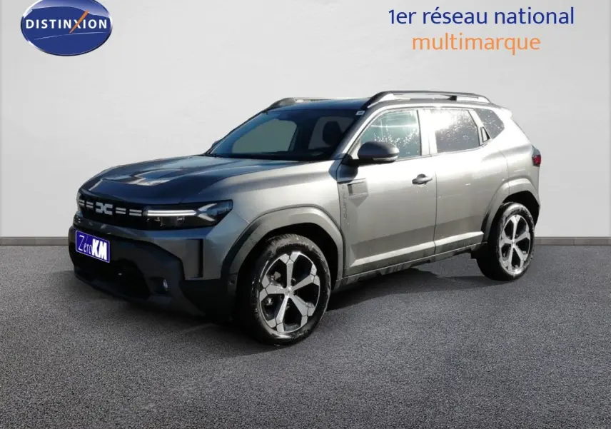 Dacia Duster gris schiste métal en 3/4 avant droit, avec jantes bi-ton et barres de toit visibles.