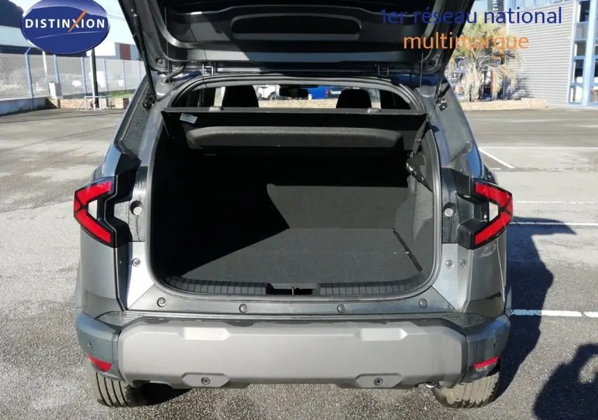 Vue arrière du Dacia Duster gris schiste métal 2026 avec coffre ouvert et feux arrière allumés.