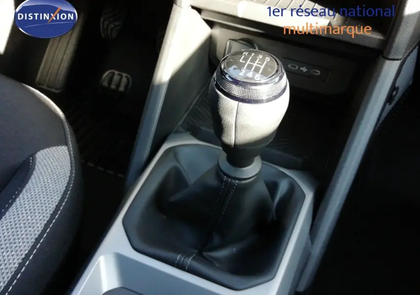 Gros plan sur le levier de vitesses manuel du Dacia Duster gris schiste métal, avec sellerie tissu visible à gauche.