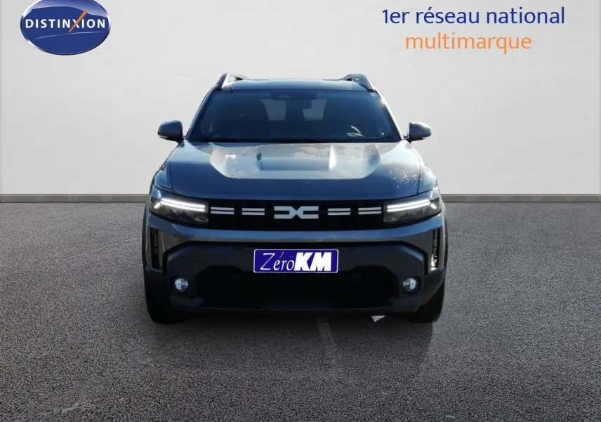 Vue frontale d'un Dacia Duster TCE MHEV 140ch Journey gris schiste métal avec calandre distinctive et feux LED allumés.