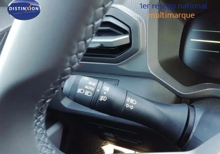 Gros plan sur la commande des feux et clignotants côté gauche du volant d’un Dacia Duster gris schiste métal 2026.