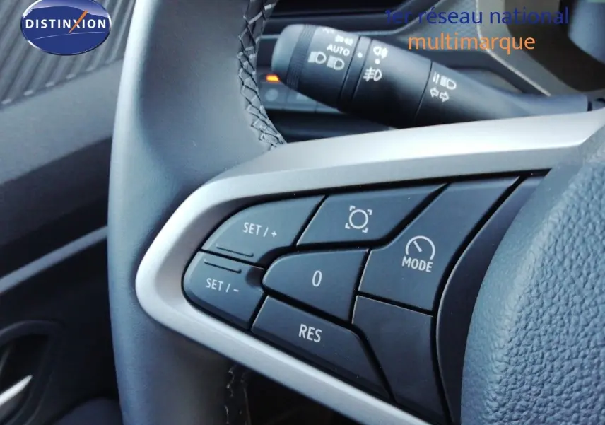 Gros plan sur les commandes au volant du Dacia Duster 2026, boutons de régulateur de vitesse visibles en noir et gris.