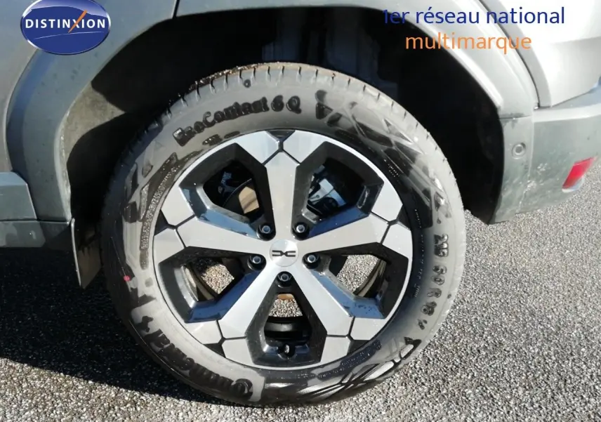 Gros plan sur la roue avant droite du Dacia Duster gris schiste métal avec jante alliage bicolore.