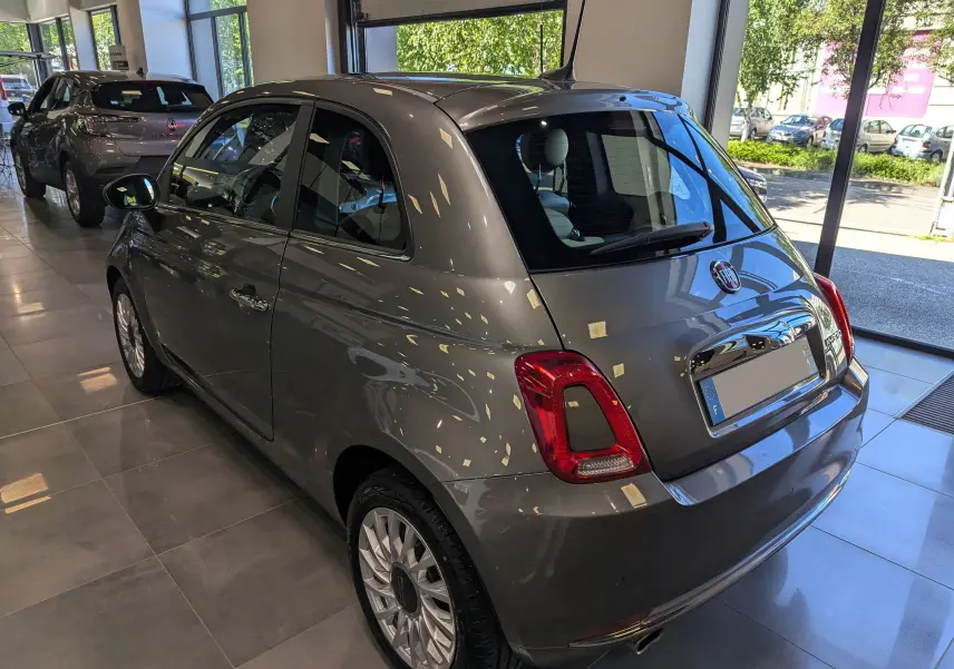 Vue 3/4 arrière droite de la Fiat 500 hybride 2021 en Electroclash Grey, stationnée en showroom lumineux.