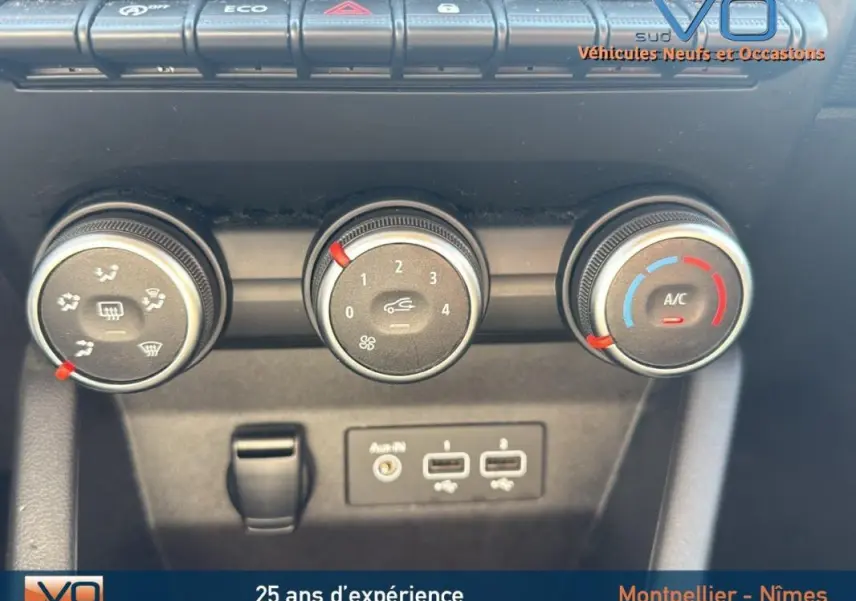 Gros plan sur les commandes de climatisation manuelle et connectiques USB de la Renault Clio gris 2022.