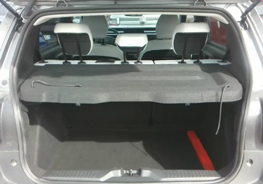 Vue arrière du coffre ouvert d'une Citroën C3 gris Mercury, montrant les appuie-têtes blancs et la tablette arrière.