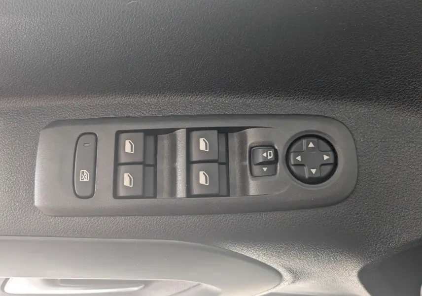 Vue rapprochée des commandes de lève-vitres et réglage des rétroviseurs sur la porte intérieure noire d'un Citroën Berlingo beige.