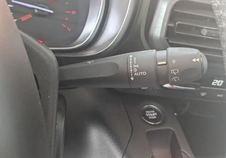 Gros plan sur la commande des essuie-glaces à gauche du volant dans l'habitacle gris noir du Citroën Berlingo beige 2019.