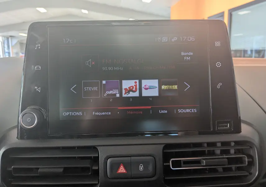Écran tactile central du tableau de bord du Citroën Berlingo 2019, affichant les stations radio FM en intérieur beige.
