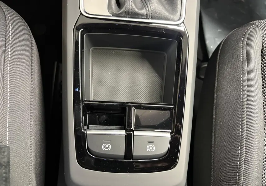 Vue plongeante sur la console centrale noire de l'Audi Q2 35 TFSI S Line avec boutons de frein à main et auto hold.