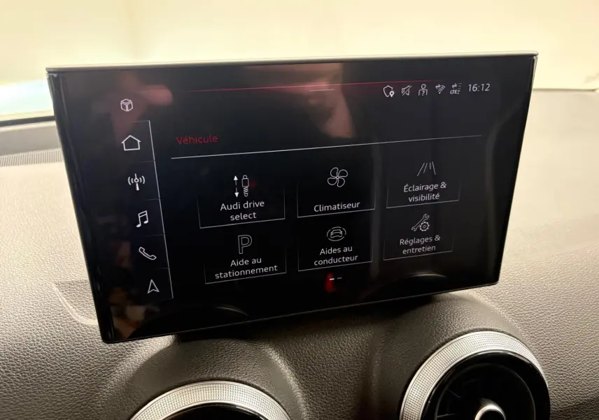 Écran tactile central de l’Audi Q2 35 TFSI S Line 2026 affichant les réglages du véhicule, avec deux aérateurs ronds en dessous.