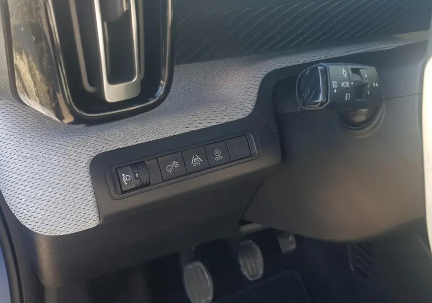 Détail intérieur côté gauche du tableau de bord bleu foncé de la Citroën C3 2024 avec commandes d’éclairage et pédales visibles.