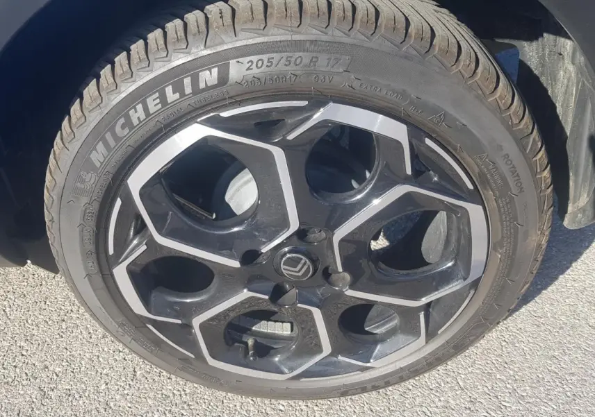 Gros plan sur la jante alliage 17 pouces noire et argentée d'une Citroën C3 bleu foncé, avec pneu Michelin visible.