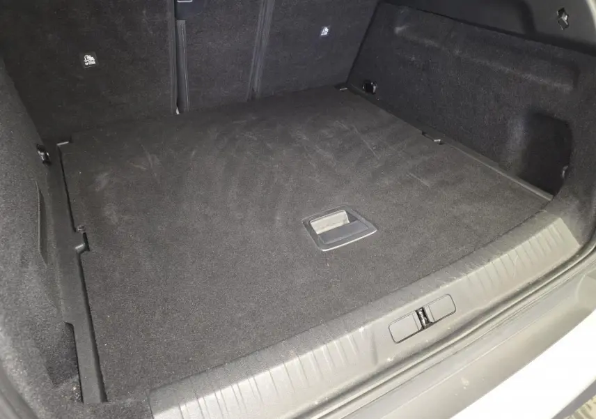 Coffre spacieux et propre du Peugeot 3008 gris, vue intérieure arrière avec plancher plat et poignée centrale.