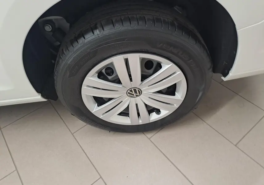 Gros plan sur la roue avant gauche blanche du Volkswagen Caddy Cargo Maxi 2026 avec jante argentée et pneu noir.