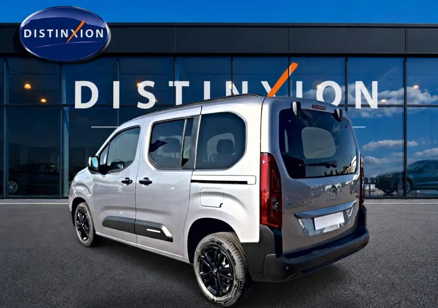 Vue 3/4 arrière droite du Citroën Berlingo Steel Grey avec jantes alu noires et barres de toit visibles.