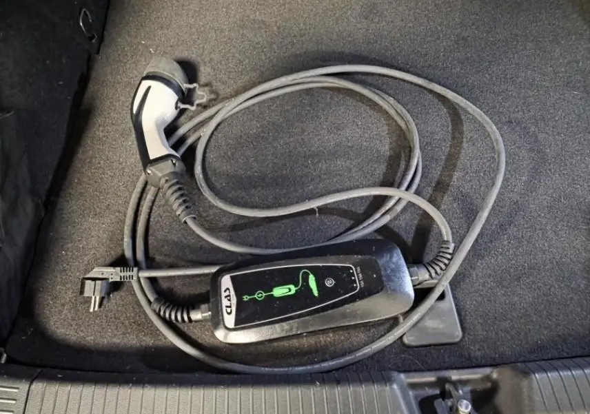 Câble de recharge noir pour Volkswagen Golf hybride rechargeable posé dans le coffre au revêtement gris.