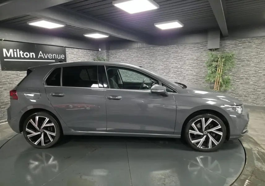 Volkswagen Golf 8 hybride rechargeable gris vue de profil côté gauche avec jantes alliage 18 pouces en intérieur showroom.