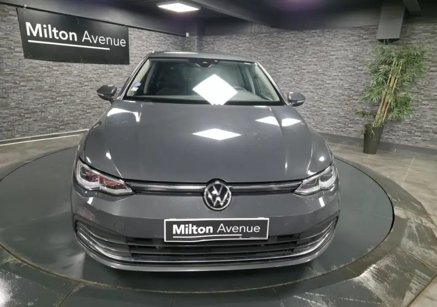 Volkswagen Golf 1.4 eHybrid gris vue de face en intérieur avec logo VW et plaque Milton Avenue visible