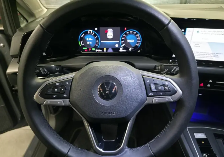 Vue intérieure centrée sur le volant noir de la Volkswagen Golf 1.4 eHybrid 2020 avec tableau de bord digital lumineux.