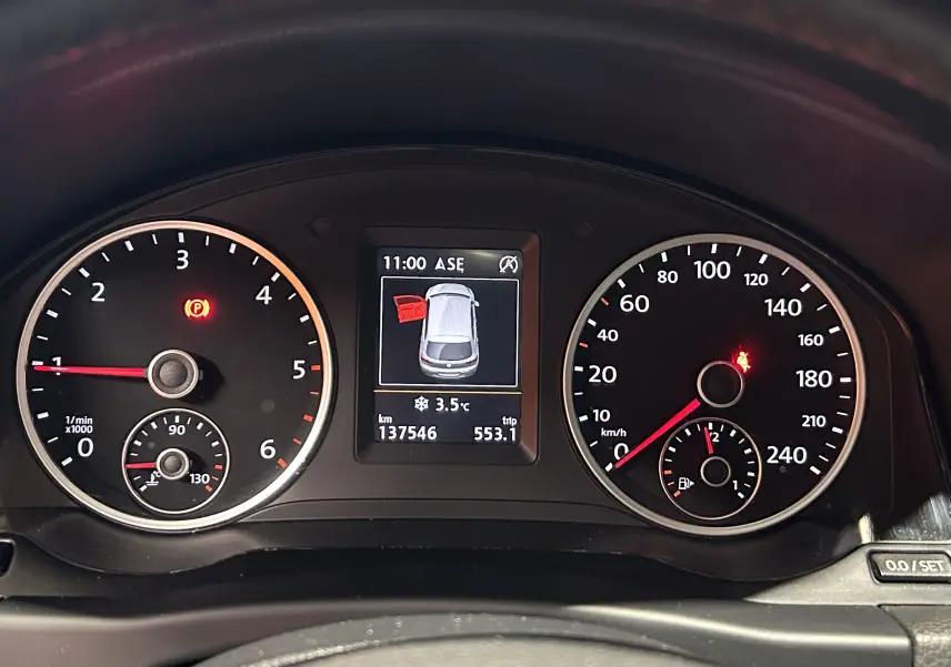 Vue rapprochée du tableau de bord du Volkswagen Tiguan 2015 affichant compte-tours, vitesse et écran central avec porte ouverte.