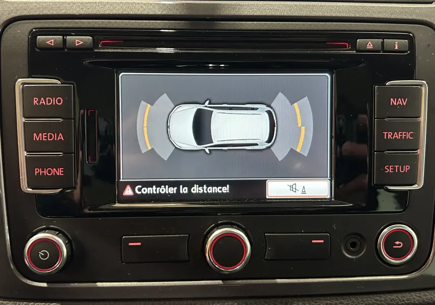 Vue rapprochée de l'écran central du Volkswagen Tiguan 2015 affichant l'alerte de contrôle de distance au stationnement.