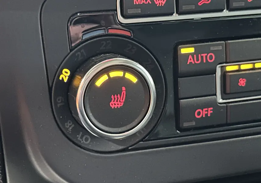 Gros plan sur le bouton de réglage de la température et siège chauffant actif dans le Volkswagen Tiguan noir métal 2015.