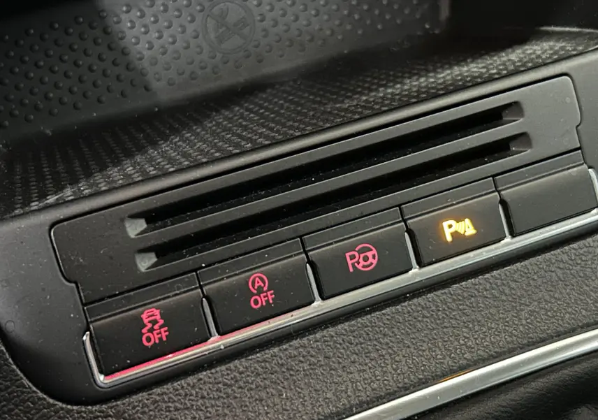 Gros plan sur les boutons de contrôle du tableau de bord du Volkswagen Tiguan noir, avec voyants rouges et orange allumés.