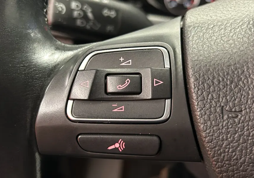 Gros plan sur les commandes de volume et téléphone au volant en cuir noir du Volkswagen Tiguan 2015.