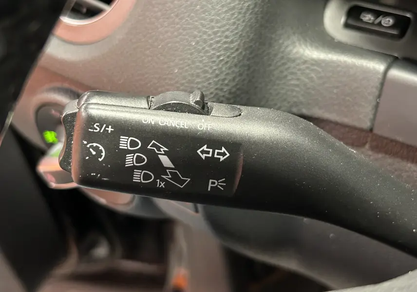 Gros plan sur la manette de clignotants et régulateur de vitesse dans l'habitacle du Volkswagen Tiguan noir 2015.