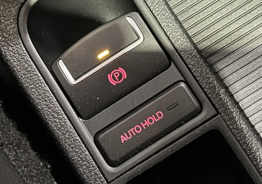 Gros plan sur les commandes de frein à main électronique et Auto Hold du Volkswagen Tiguan noir métal de 2015.