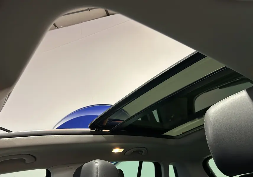 Toit ouvrant panoramique ouvert vu de l'intérieur d'un Volkswagen Tiguan noir métal avec sièges cuir gris.