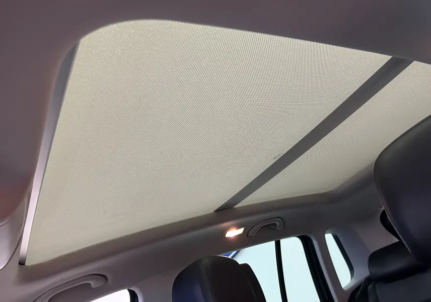 Toit ouvrant panoramique avec pare-soleil déployé et sièges en cuir noir à l'intérieur d'un Volkswagen Tiguan.