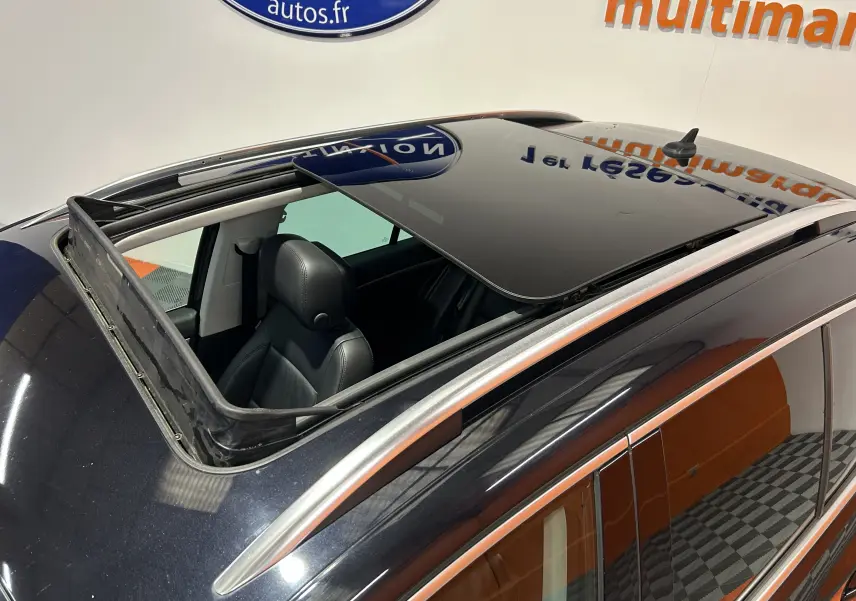 Toit ouvrant panoramique ouvert vu de dessus sur Volkswagen Tiguan noir métal avec sièges en cuir visibles côté gauche.