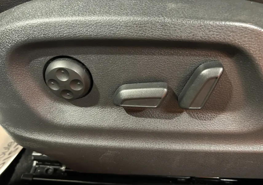 Commandes de réglage électrique des sièges en cuir dans un Volkswagen Tiguan noir métal de 2015.