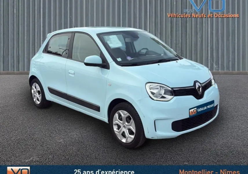 Renault Twingo III bleu clair vue 3/4 avant droit sur fond gris avec logo VO sur plaque avant.