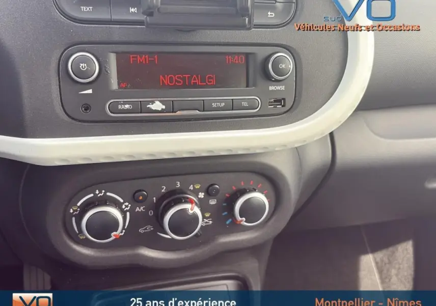 Détail du tableau de bord de la Renault Twingo III bleu clair, avec commandes de climatisation manuelle et radio affichant "NOSTALGI".