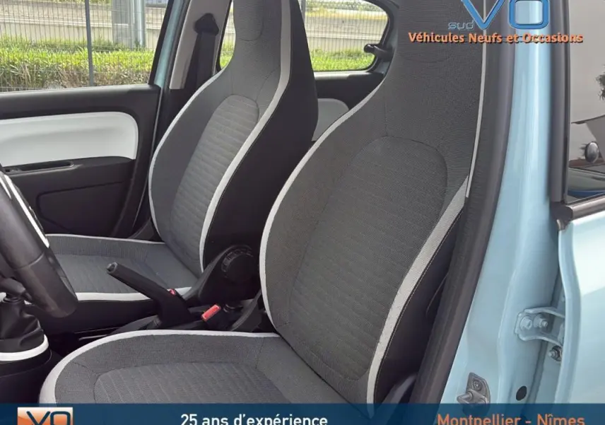 Vue intérieure côté gauche de la Renault Twingo III bleu clair, montrant les sièges avant gris avec contours clairs.