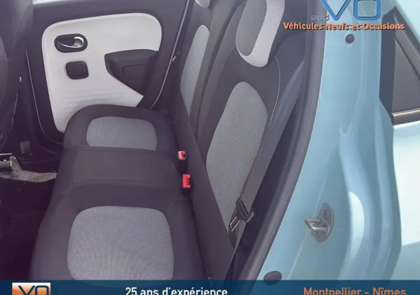 Vue intérieure côté gauche des sièges arrière gris et noir d'une Renault Twingo III bleu clair avec porte ouverte.