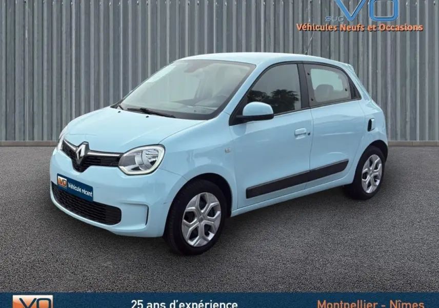 Renault Twingo III bleu clair vue 3/4 avant droit, compacte et moderne sur fond neutre urbain.