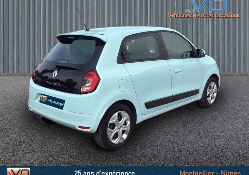 Renault Twingo III bleu clair vue 3/4 arrière droit, avec toit noir et jantes argentées, stationnée sur sol gris.