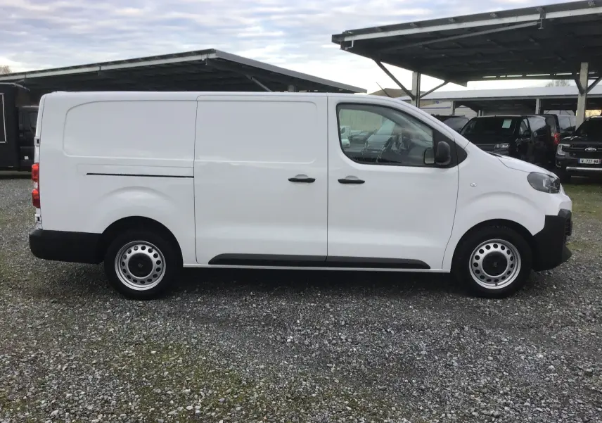 Fiat Scudo Fourgon blanc vu de profil côté droit, avec porte coulissante et jantes acier simples.