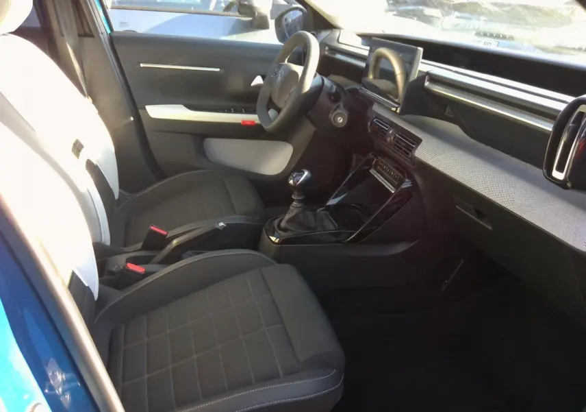 Vue intérieure côté conducteur de la Citroën C3 Bright Blue avec tableau de bord moderne et boîte manuelle.