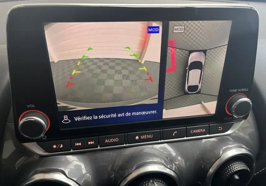 Écran tactile intérieur du Nissan Juke Hybrid gris clair 2024 montrant la caméra de recul et vue 360° en stationnement.