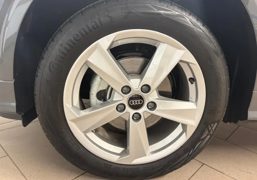 Gros plan sur la roue avant gauche de l'Audi Q2 35 TFSI S Line 2026 en gris Daytona avec jante alliage cinq branches.