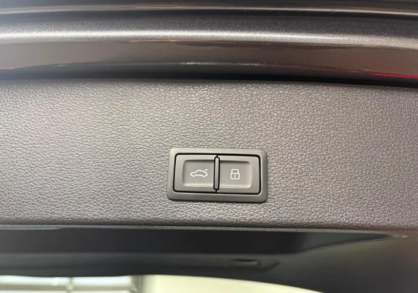 Boutons de commande du hayon électrique et de verrouillage intégrés sur la garniture intérieure du coffre d'un Audi Q2 gris Daytona.