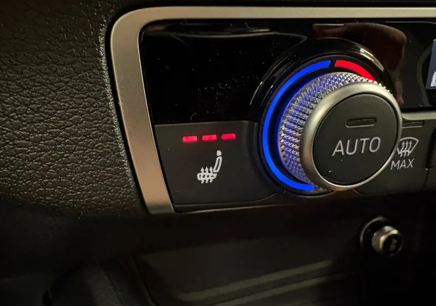 Gros plan sur la commande de siège chauffant et réglage automatique de la climatisation dans l'Audi Q2 Gris Daytona.