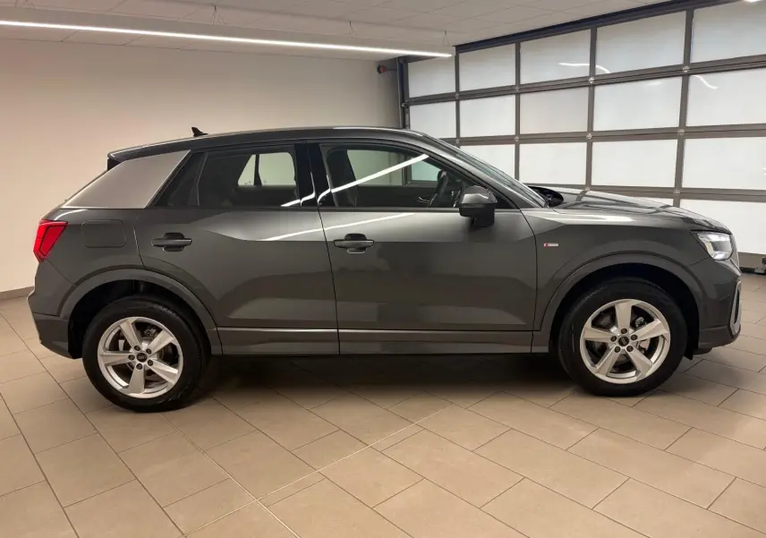 Audi Q2 35 TFSI S Line gris Daytona vue de profil côté gauche dans un garage, avec jantes alliage visibles.