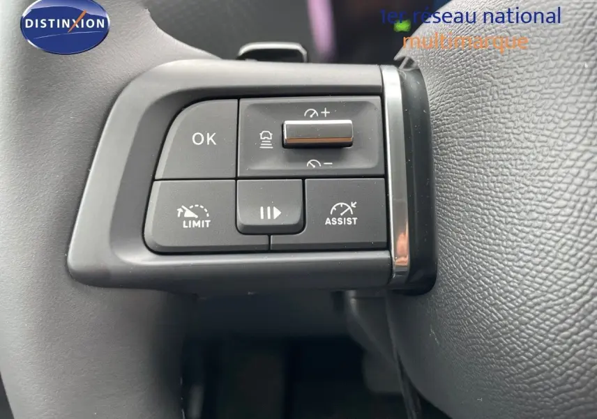 Gros plan sur les commandes au volant gauche du Citroën C4 blanc métal 2024, avec boutons d'assistance et régulateur.